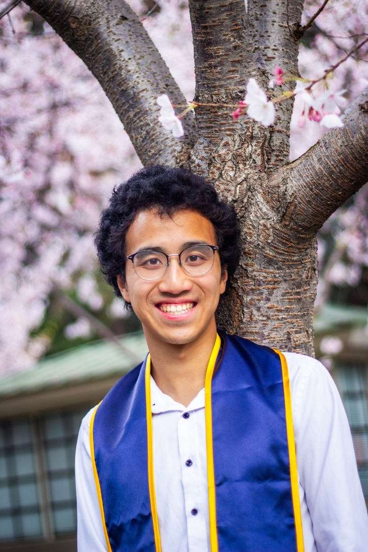 Qi Jia (Jerry) Sun standing in front of flowering cherry trees